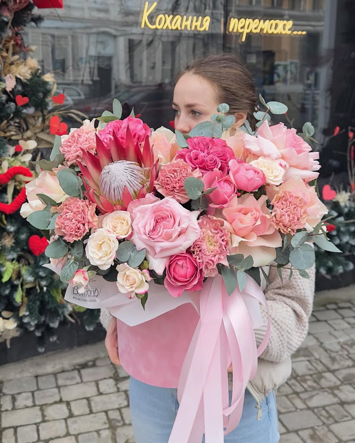 Flower bouquet with protea and roses in a vase with pink ribbons
