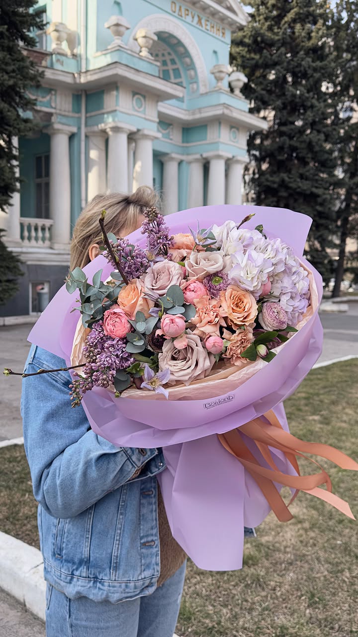 Delicate spring bouquet with lilacs and roses in lilac wrapping