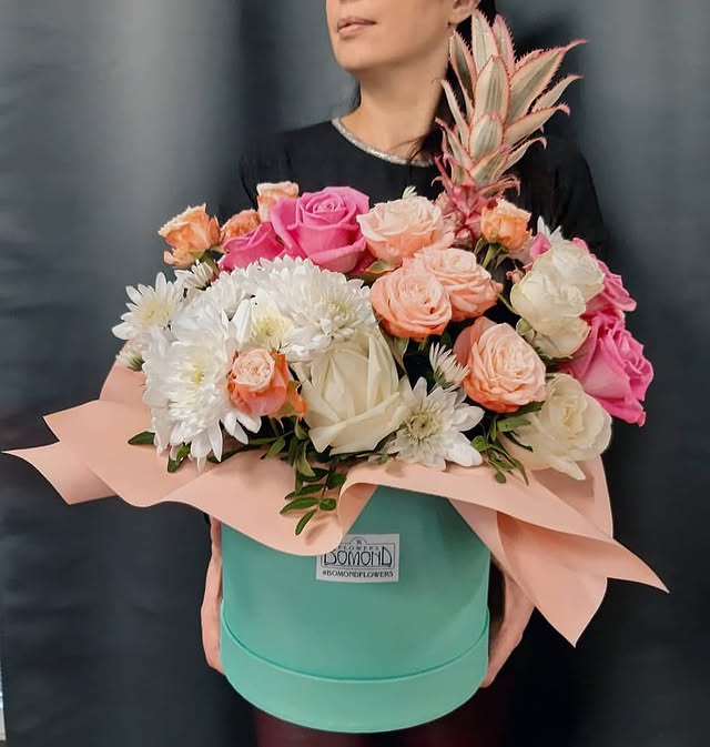 Flower arrangement in a box with roses and pineapple
