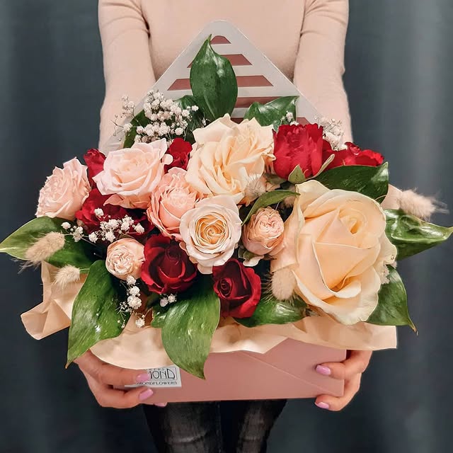 Flower arrangement in an envelope with cream and red roses