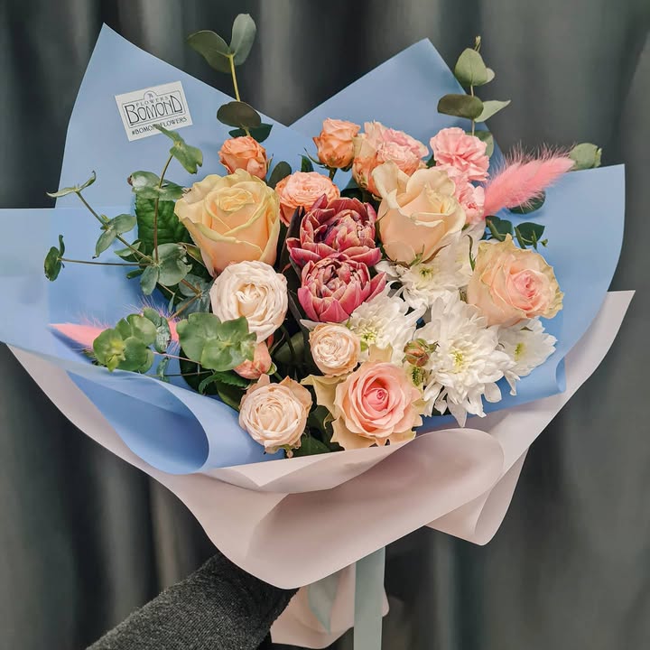 Bouquet of delicate roses and chrysanthemums in blue and white wrapping