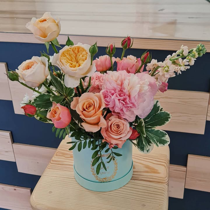 Exclusive flower arrangement in blue hat box with roses and peony-like flowers