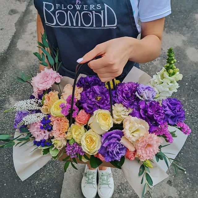 Fresh flower arrangement in a handbag with purple and yellow hues
