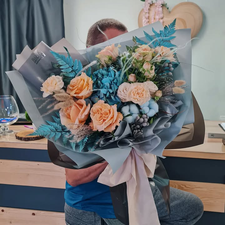 Bouquet of peach roses and blue hydrangea in stylish wrapping