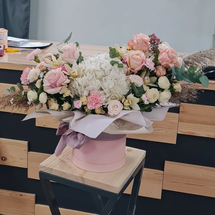 Arrangement of delicate roses and hydrangea in a hat box