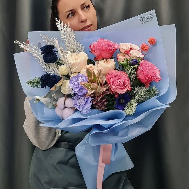 New Year bouquet with roses and coniferous elements in blue wrapping