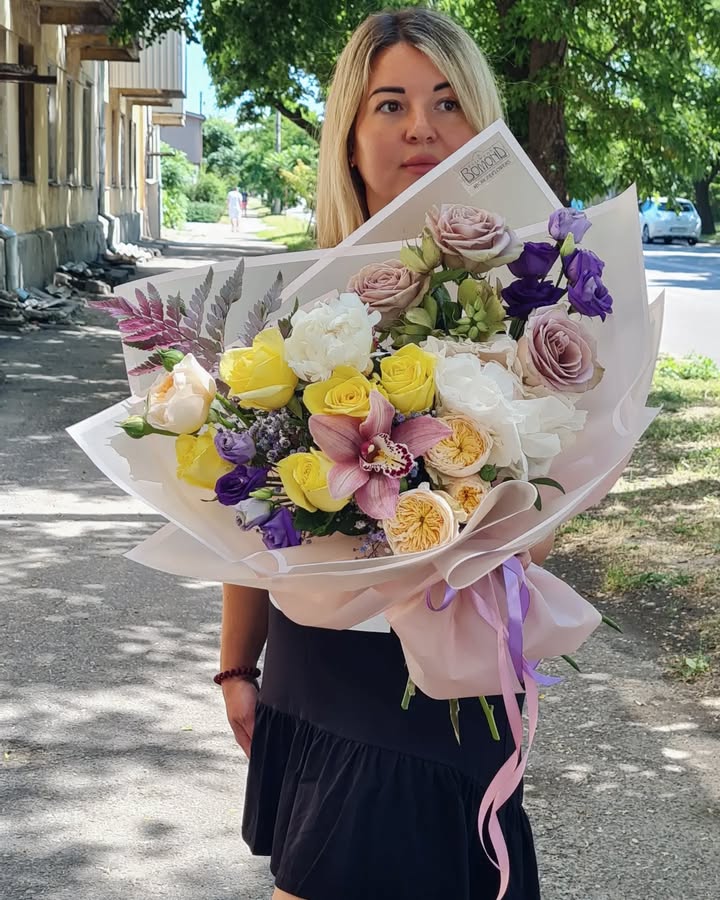 Bouquet of roses, orchid, and peonies with yellow, white, and lavender flowers