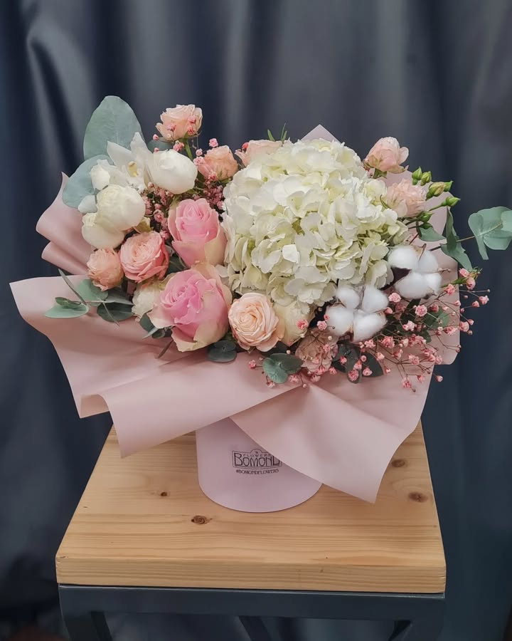 Arrangement of white hydrangea, pink roses, and cotton in a box