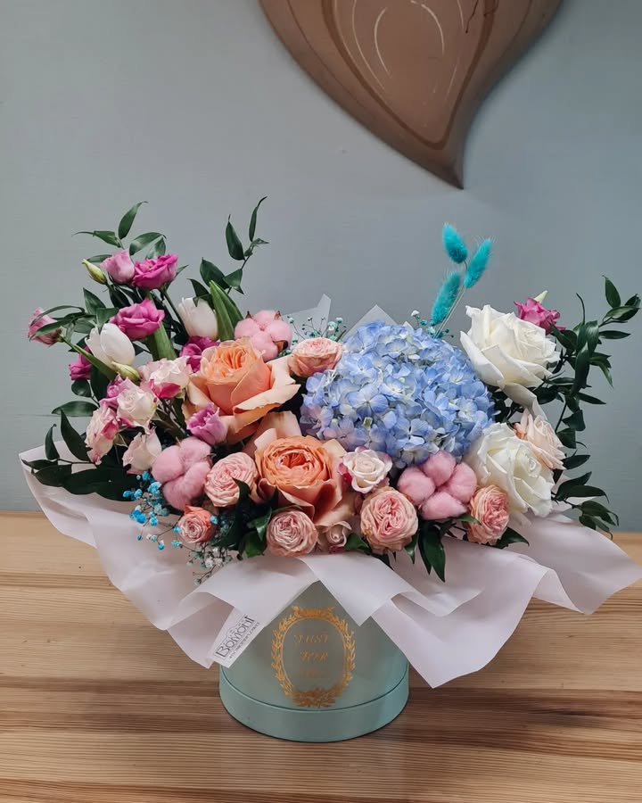 Floral arrangement with roses, hydrangea, and cotton in a box