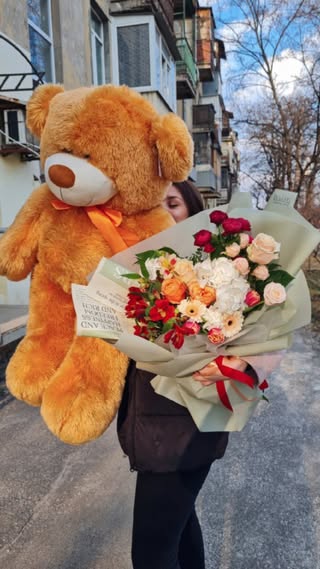 Large soft plush teddy bear with a bright flower bouquet