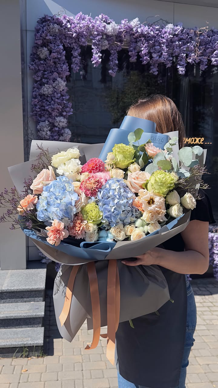 Large bouquet of hydrangeas, roses, and fresh flowers with blue wrapping