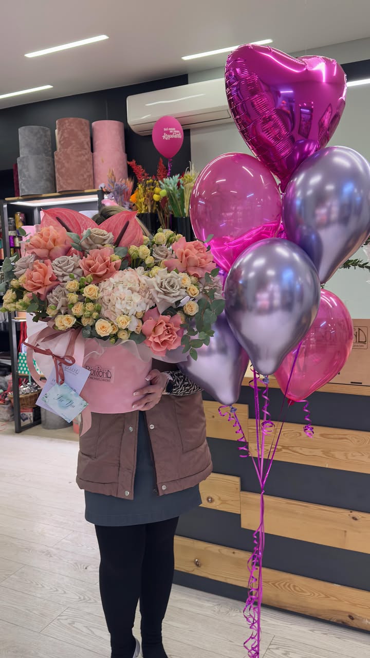 Large bouquet of pink and peach flowers in a gift box with helium balloons