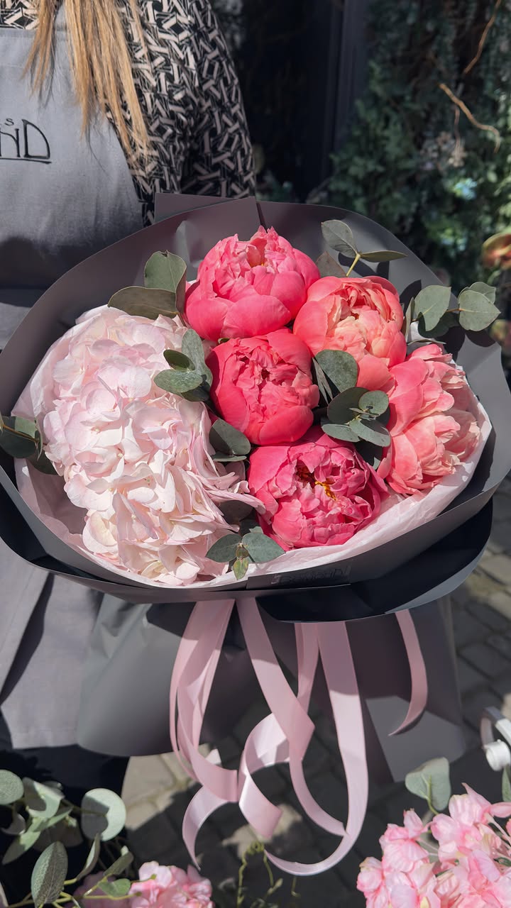 Bouquet of vibrant peonies and delicate hydrangea in elegant wrapping