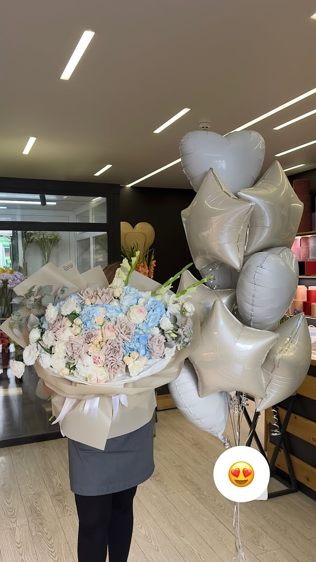 Large bouquet of delicate blue and cream flowers with decorative wrapping