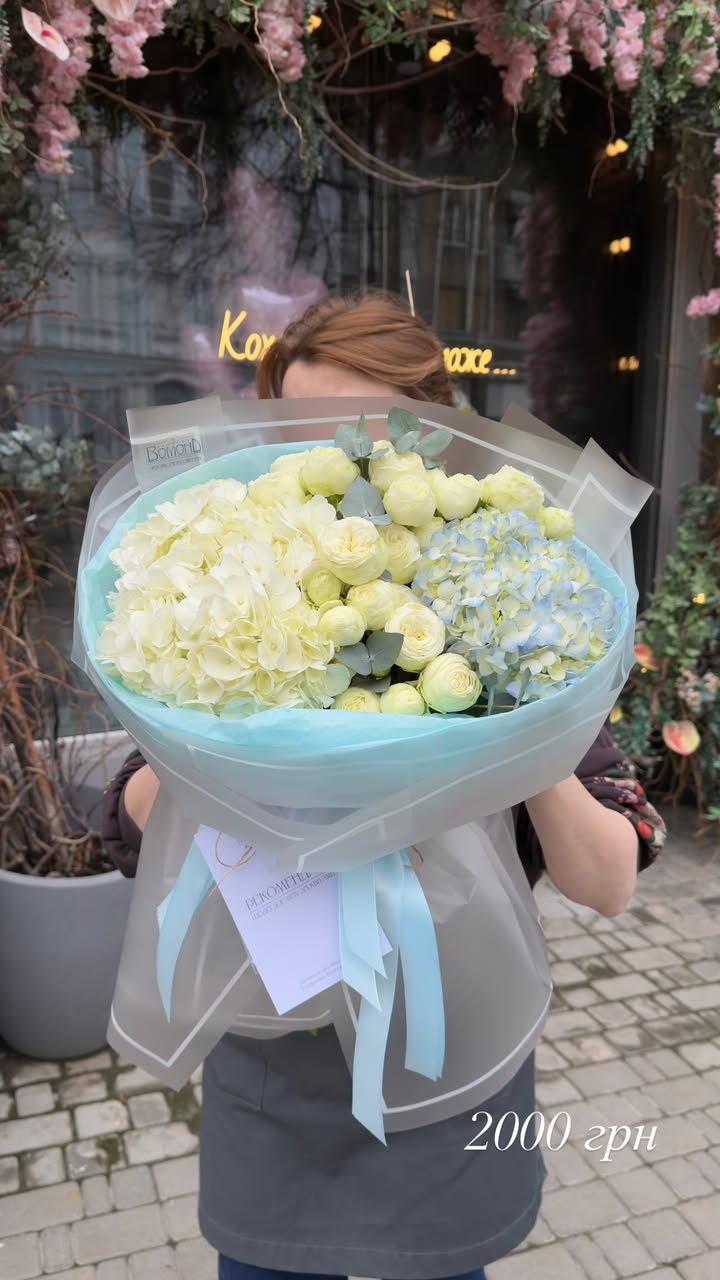 Bouquet of hydrangeas and cream ranunculus in stylish blue wrapping