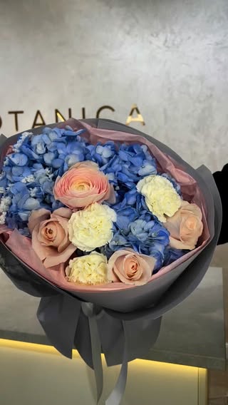 Букет з блакитної гортензії та кремових троянд у стильній сірій упаковці
