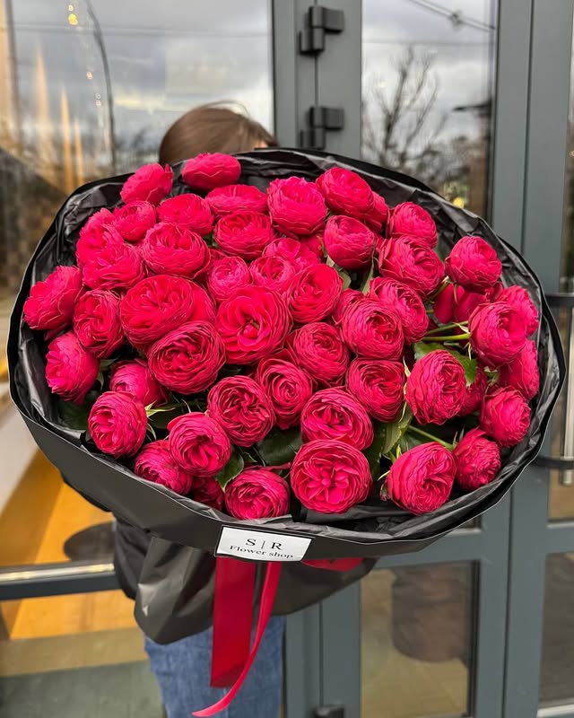 Великий букет рожевих ранункулюсів у чорній упаковці