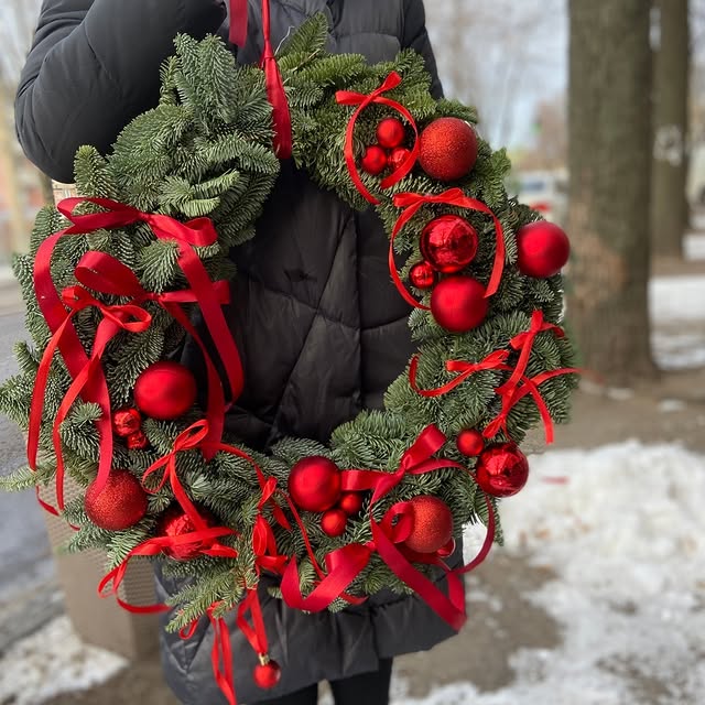 Новорічний вінок з живої ялини з червоними кулями та стрічками